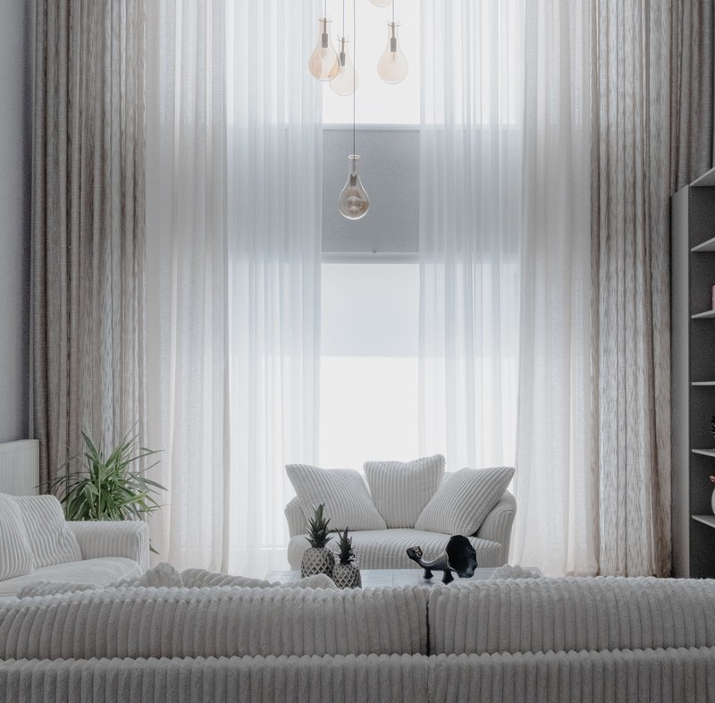 Helles Wohnzimmer mit Sofa und hohen Vorhängen